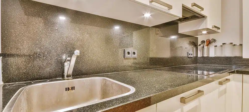 General view of the kitchen in a light color with marble countertops and white furniture in a cozy house
