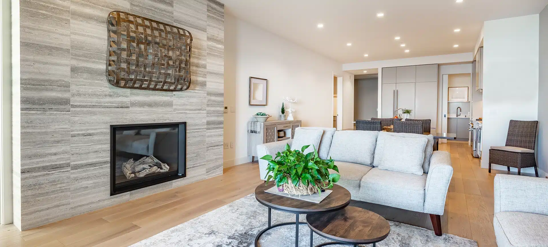 Interior living room with fireplace stone and wood mantle staircase wooden flooring decorated and staged large bright windows classic and modern decor