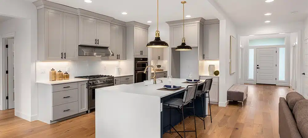Kitchen in new luxury home with waterfall island, stainless steel appliances, pendant lights, and hardwood floors