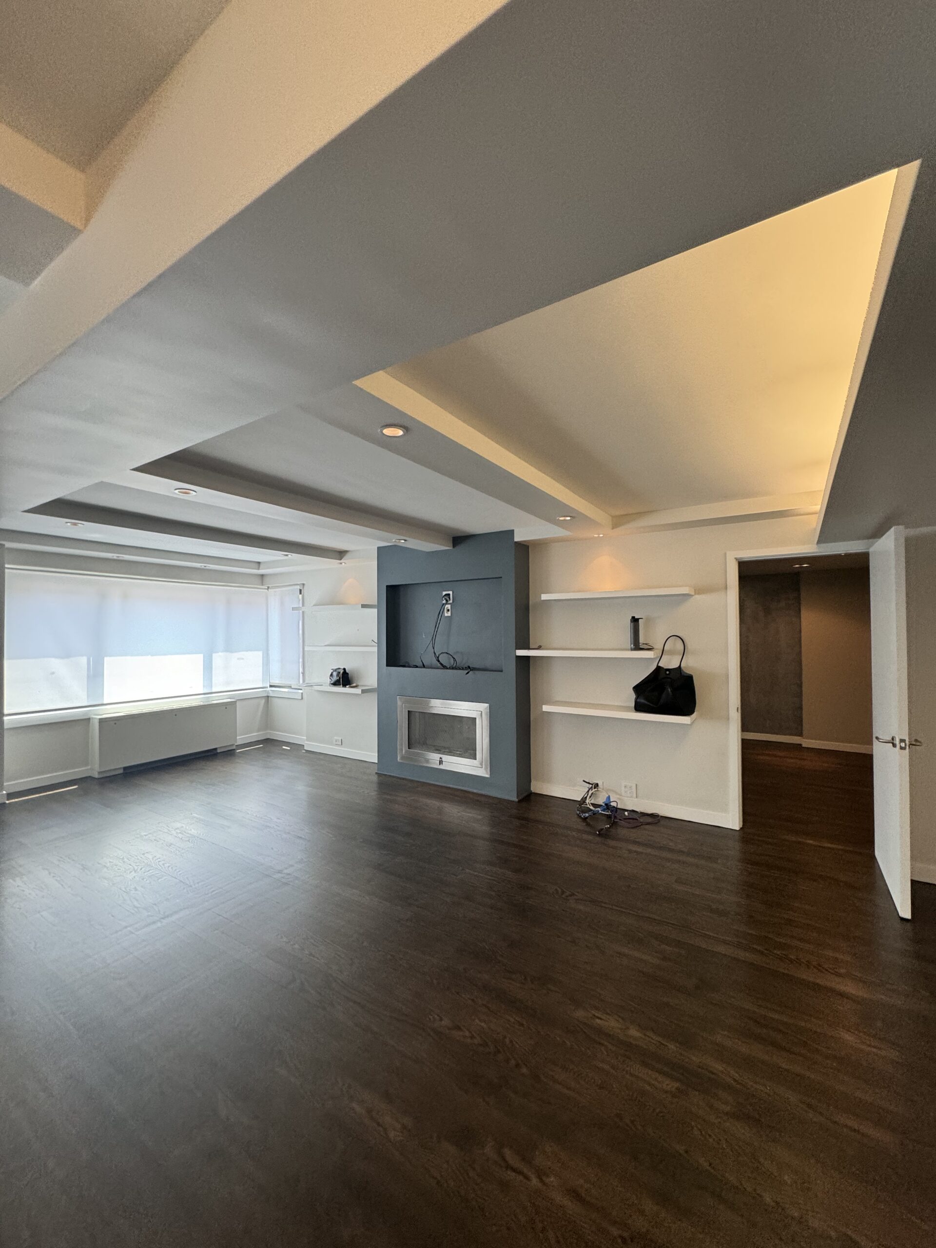 The living room at 10 East End Avenue before the renovation, with the built-in shelving, fireplace surround and sheetrock wall that were demolished