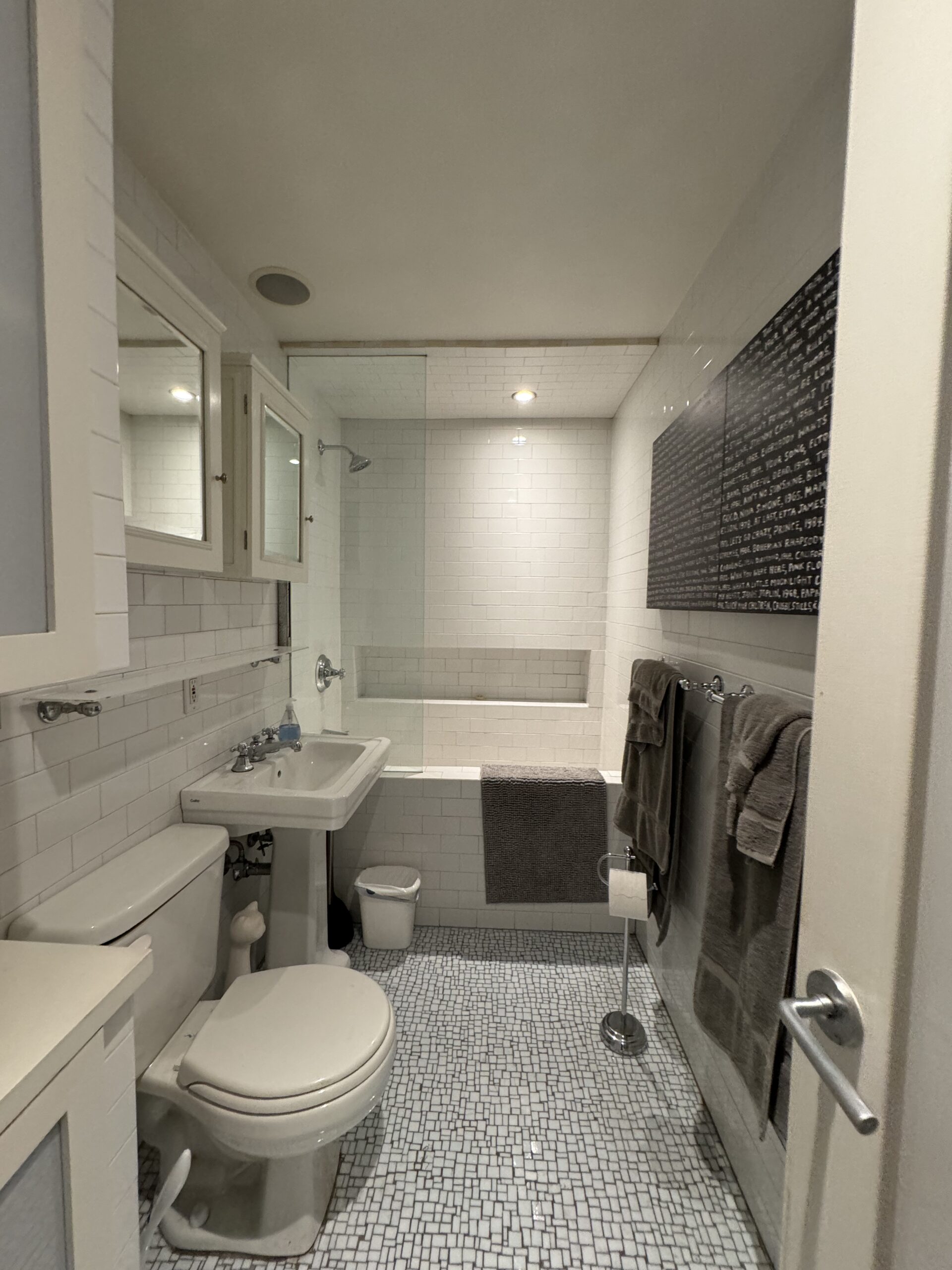 The powder room at 301 East 22nd Street before the renovation, a full bathroom with a tub, pedestal sink, tank toilet and white subway tile