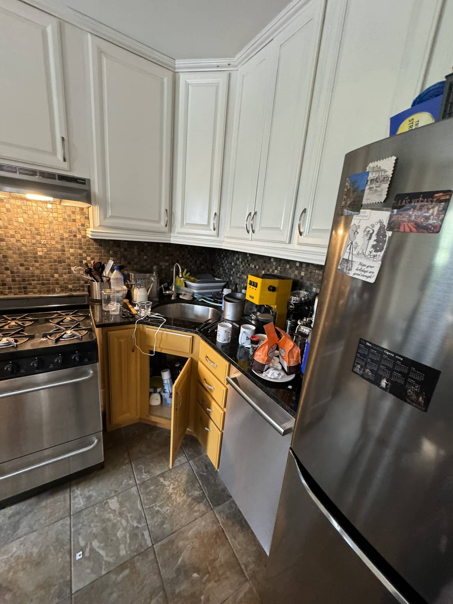 The original kitchen with honey oak base cabinets, white uppers, a dark mosaic backsplash and slate-look floor tile