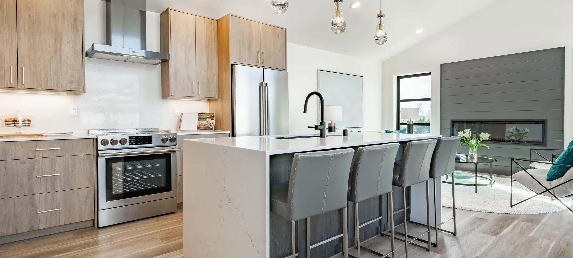 Kitchen and dining room interior with light colors aqua blue hardwood flooring grey chairs bar stools kitchen island stainless appliances and large windows