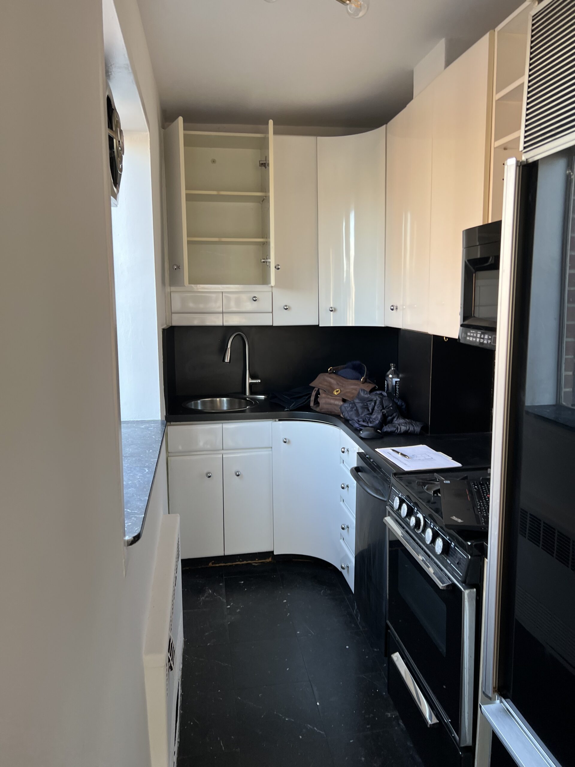 The kitchen before work at 15 West 12th Street, with the freestanding gas range, the corner sink and the wall cabinets under the soffit