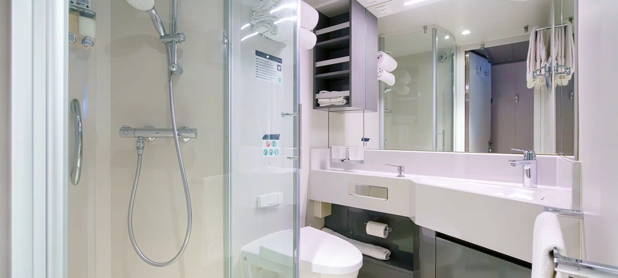 panoramic view of the bathroom with shower, sink and toilet, brightly illuminated by overhead light