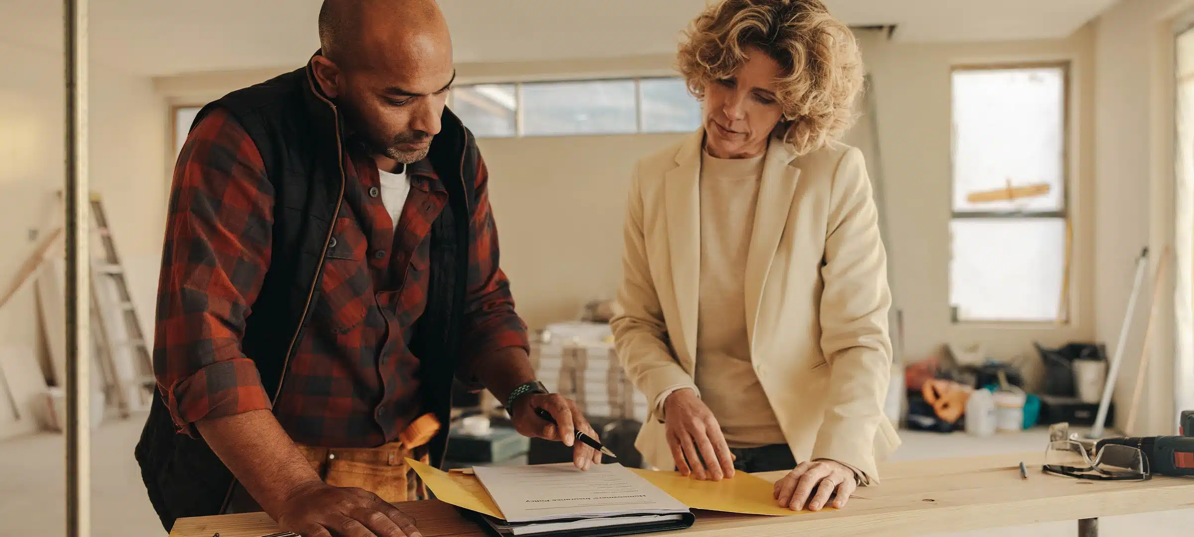 Mature contractor and homeowner signing a contract indoors for a home renovation project. They demonstrate professionalism and dedication to their work, ensuring a successful remodelling experience.