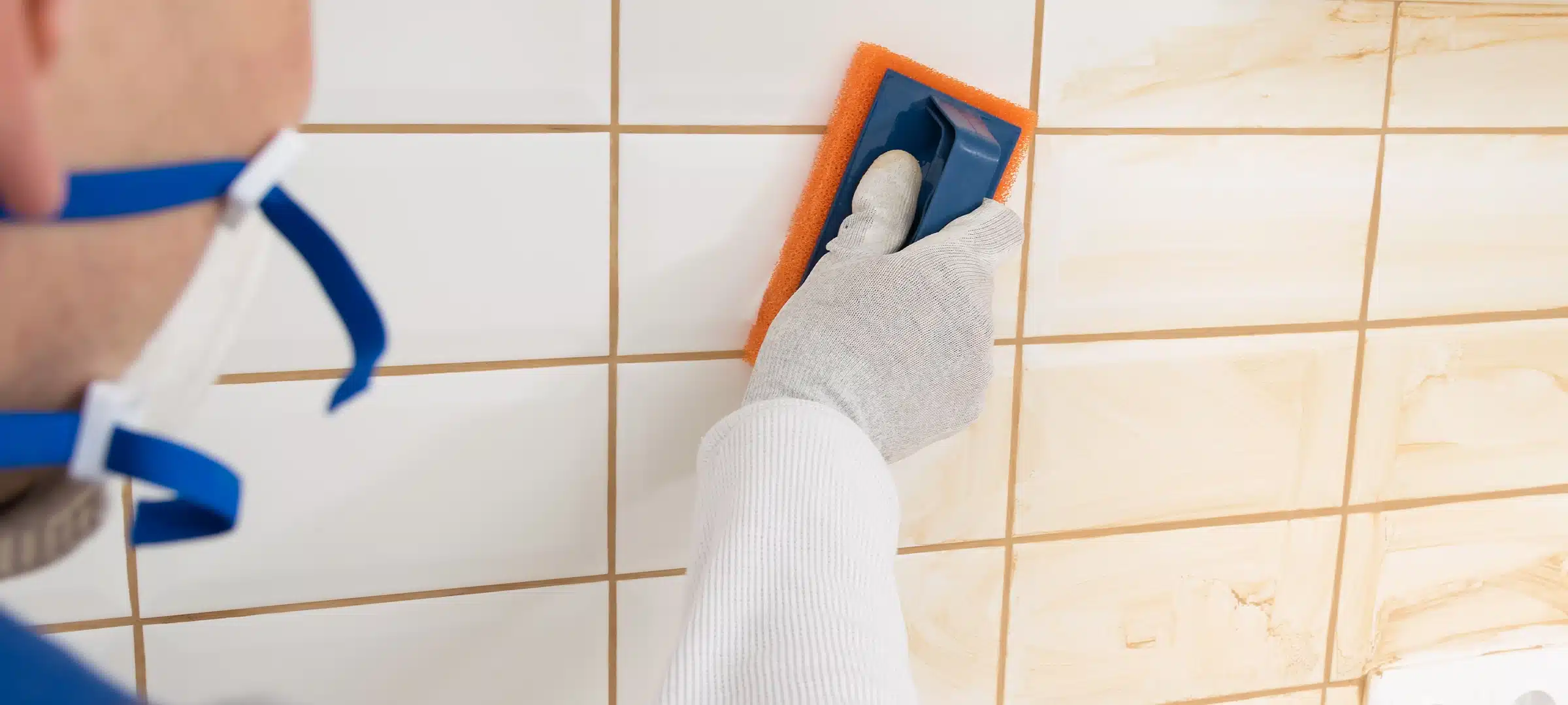 the master rubs the brown grout on white tiles with a special sponge, finishing work