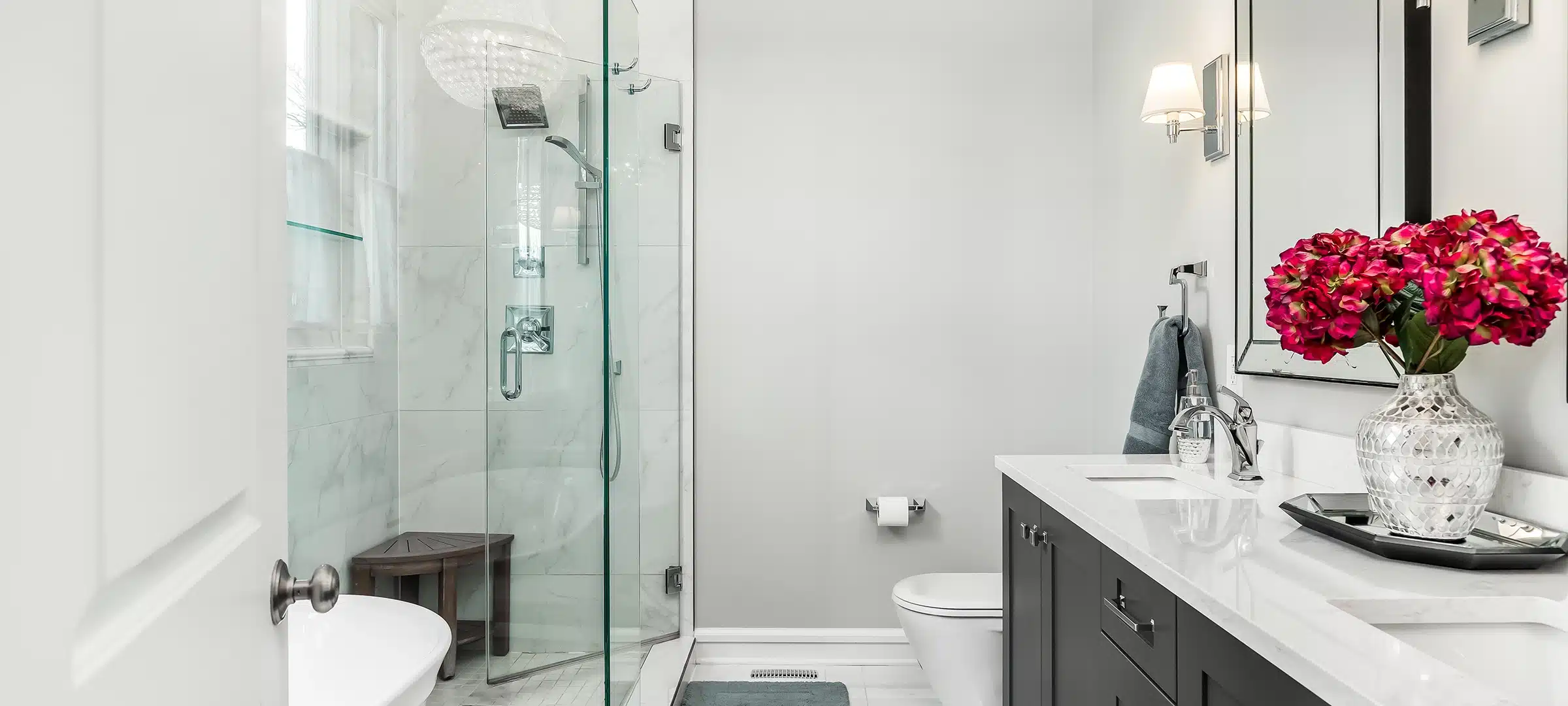 luxurious bathroom with a standalone tub, glass shower, grey double vanity, and quartz counter top.