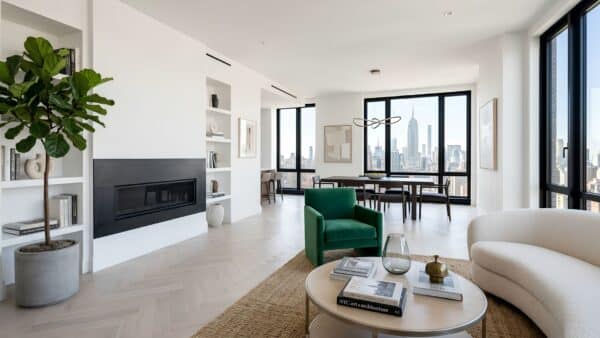 Architectural open-concept living room renovation with herringbone wood floors, a minimalist fireplace, and expansive windows showing the New York City skyline.