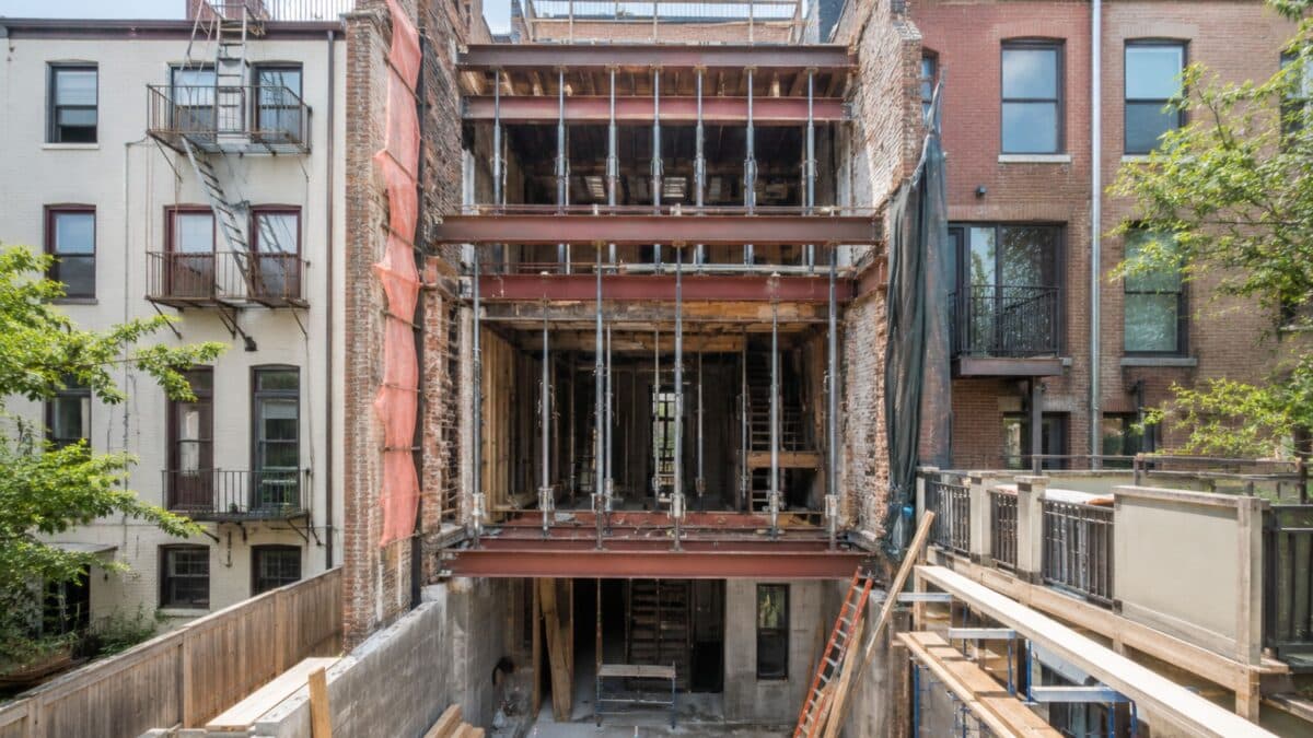 NYC brownstone undergoing structural renovation with temporary steel supports, protected party walls, and engineered construction for a single-family townhouse conversion.