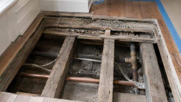 Opened pre-war apartment floor showing sleeper framing, old subfloor layers, and hidden building conditions.