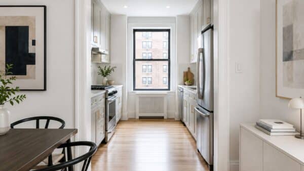 Renovated NYC apartment with a widened kitchen opening that improves circulation while preserving storage.