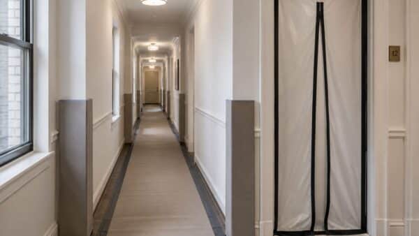 Protected apartment-building hallway prepared for renovation traffic while shared areas remain usable.