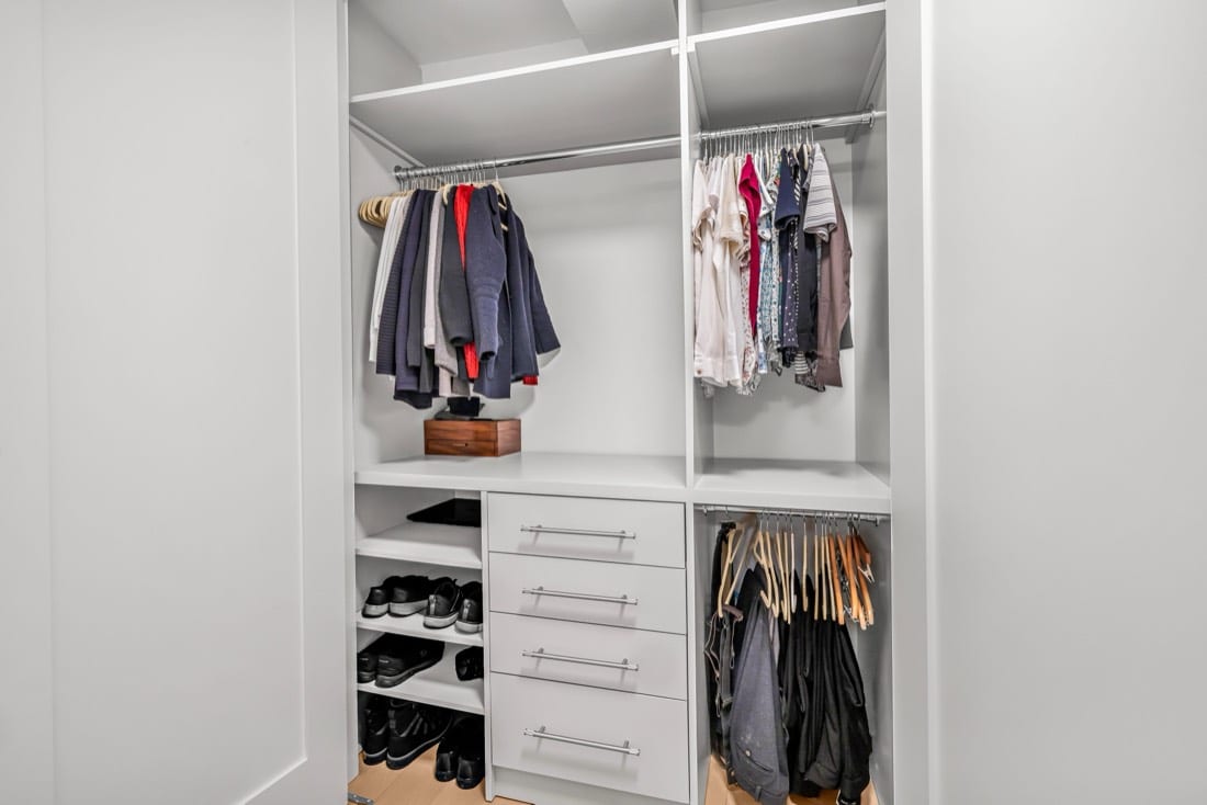Finished walk-in closet in a New Closet Summer Breeze system with hanging rails at two heights, open shelving, a drawer stack with Top Knobs satin nickel pulls and shoe shelves