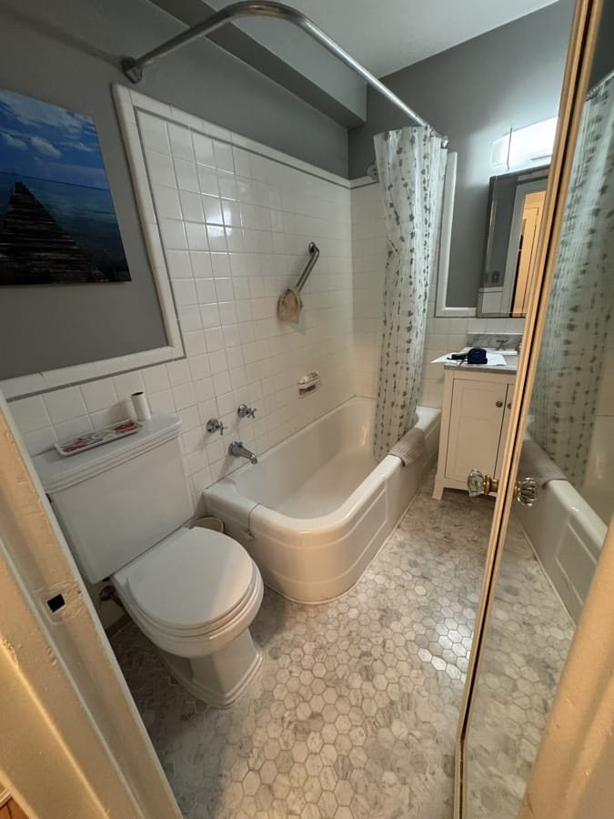 Before renovation: the original bathroom from the doorway with the toilet in the foreground and the corridor beyond