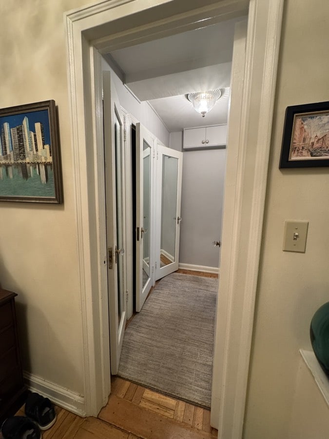 Before renovation: the entry hall with framed pictures, painted closet doors and a carpet runner over the original hardwood floor