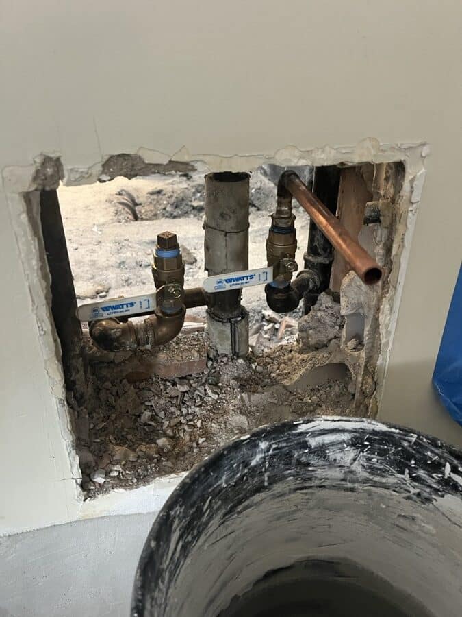 During the work at 220 Madison Avenue: The wall opened: corroded galvanised waste and supply, with new copper run in beside it.