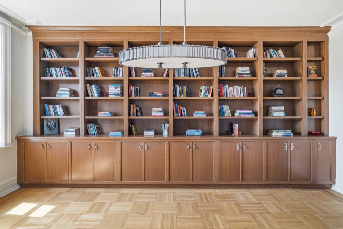 The finished dining room built-in seen from the room, with a ring pendant above and the original parquet block floor kept underfoot