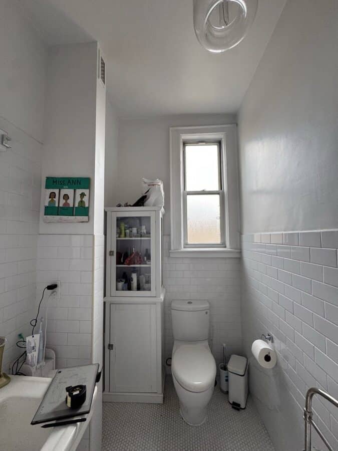 Before renovation: the window end of the original hall bathroom with the corner cabinet and toilet